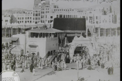 Kaaba 🕋 in the centre, partially covered on the left side by the building that housed the Zamzam well, in the centre is Bani Shaeba Gate.  c. 1963 AD (1382 AH)